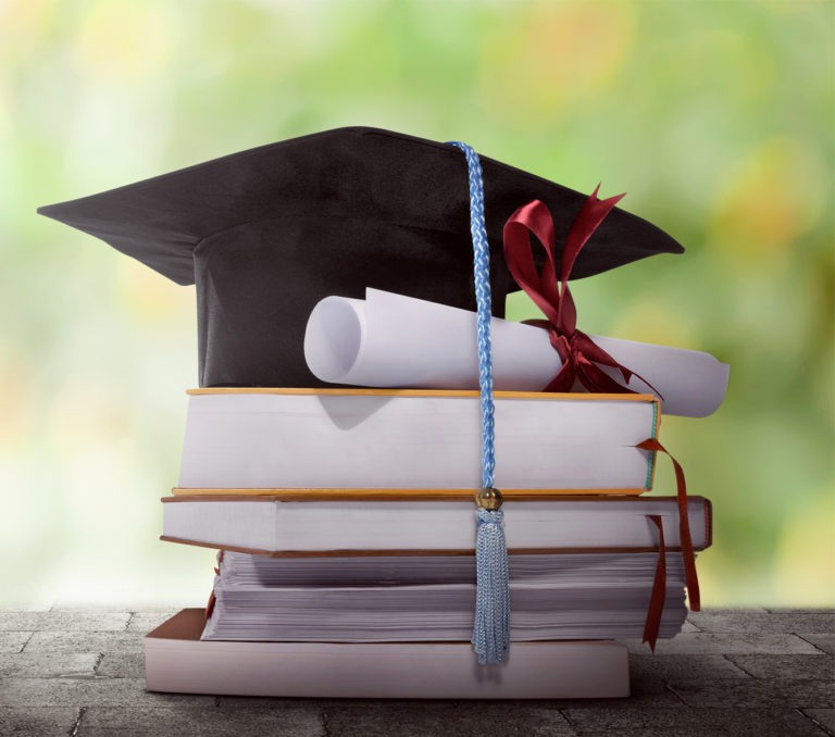 Graduation hat with diploma on a stack of book