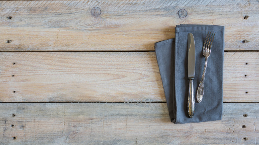 Cutlery and napkin on wooden background