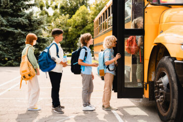 students standing in line waiting for boarding school bus