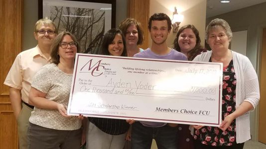 Scholarship Winner, Ayden Yoder, with staff and large check